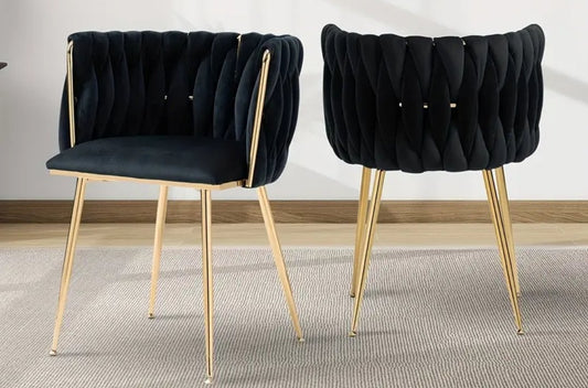Two black cushioned chairs with gold legs on a neutral background
